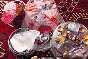 Various colorful alcoholic cocktails. Various fresh alcoholic cocktails. Dark red glasses space. Top view