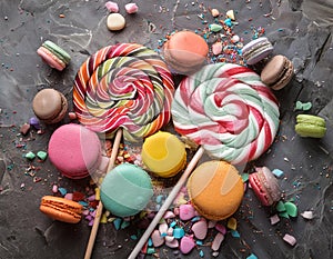 Various colorful candies, lollipops, and macaroons. Sweets on stone background