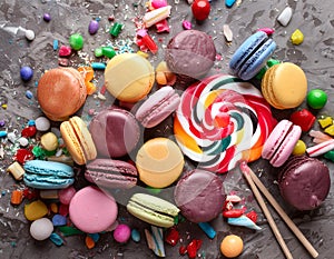 Various colorful candies, lollipops, and macaroons. Sweets on stone background