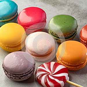 Various colorful candies, lollipops, and macaroons. Sweets on stone background