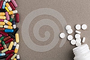 Various colorful capsules and pill bottle from white round pills