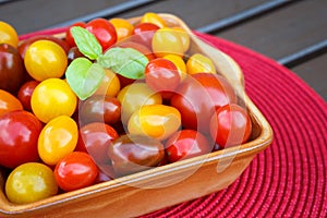 Various of colorful cherry tomatoes in a ceramic bowl.