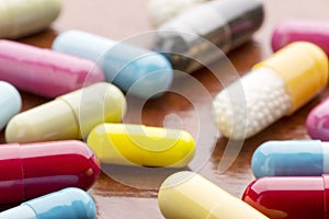 Various colorful medicine capsules on wooden background