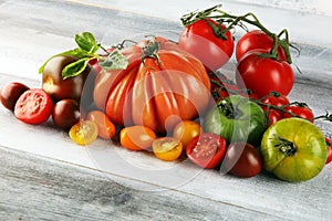 Various colorful tomatoes and basil leaves on rustic table