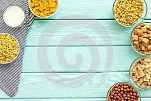 Various corn cereals in bowls and milk on mint wooden background top view copyspace