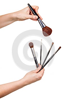 Various cosmetic makeup brushes in female hands isolated on whit