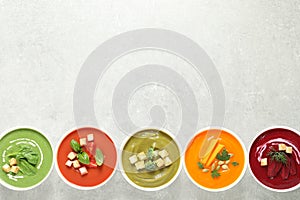 Various cream soups in bowls on grey background, top view