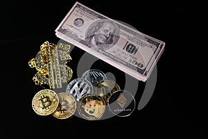 Various crypto coins lie next to a stack of 100-dollar bills, a white alarm clock and a diamond-studded dollar chain pendant