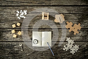 Various cubes, pegs, puzzles and a key lying on wooden desk around an open notepad