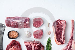 Various cuts of marbled beef meat and dry aged steaks, tomahawk, t bone, club steak, rib eye and tenderloin cuts, on white stone