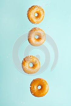 Various decorated donuts in motion falling on a blue background. Sweet and iced donuts fall or fly in motion. With coconut flakes