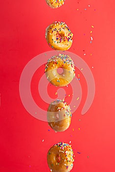Various decorated donuts in motion falling on a red background. Sweet and iced donuts fall or fly in motion. With caramel.
