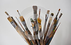 Various dirty paint brushes in a black cup isolated on white