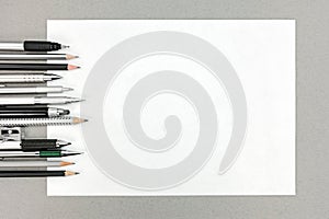 Various drawing tools and blank sheet of paper on gray office de