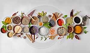 Various dry spices in small bowls and raw herbs flat lay on white background. Top view