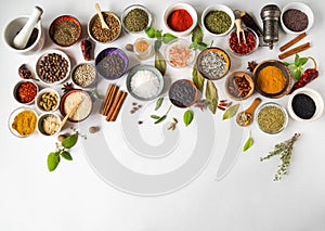 Various dry spices in small bowls and raw herbs flat lay on white background. Top view, copy space