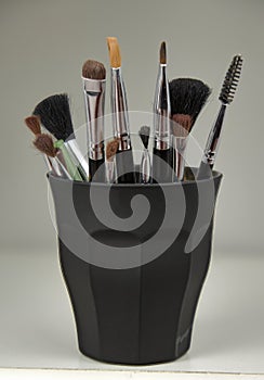 Various facial makeup brushes in a glass