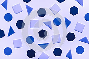 Various flat figures - circles, triangles, squares, hexagons - lie abstractly on blue cardboard. Blue tinted