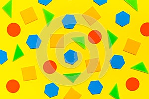 Various flat figures - circles, triangles, squares, hexagons - lie abstractly on yellow cardboard