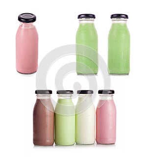 Various flavors of milk in bottles with strawberries isolated on white background.
