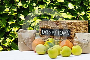 Various food in a box for donations on a table on a background of greens. Charity and donation concept, copy space.