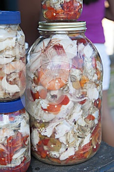 Various foods in vinegar - seafood in glass bottles for sale at a market stall.