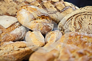 Various French breads, such as baguette, petits pains and loafs of sourdough, called pain de campagne, on display on a table.