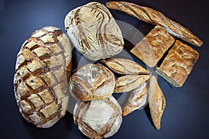 Various French breads, such as baguette, petits pains and loafs of sourdough, called pain de campagne, on display on a table.