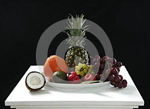 Various fresh fruits from coconut, pineapple, ripe, apples and grape on the white table in black background for healthy