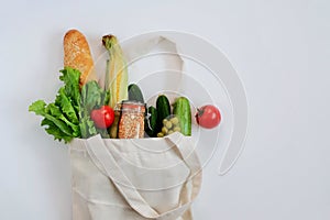 Various fresh vegetables and fruits, bread, cereals in an eco reusable bag.