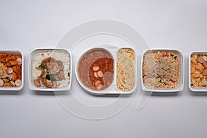 Various frozen meal in plastic tray on white background.