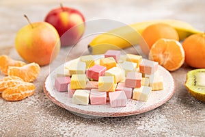 Various fruit jelly chewing candies on brown concrete. apple, banana, tangerine, side view, selective focus