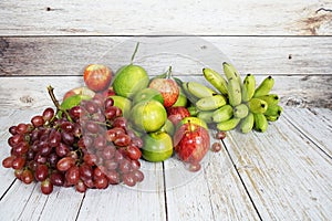 Various of fruits with Red grape, red apple, banana and green orange on wooden background