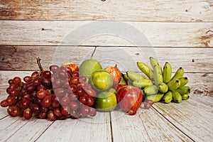 Various of fruits with Red grape, red apple, banana and green orange on wooden background