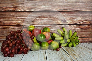 Various of fruits with Red grape, red apple, banana and green orange on wooden background