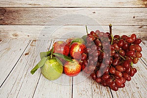 Red grape, red apple and green orange with space copy on wooden background