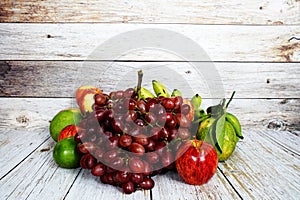 Various of fruits with Red grape, red apple and green orange on wooden background