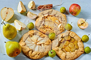 Various fruits tarts decorated with spices - cinnamon sticks on the gray concrete background. Vegetarian healthy galette