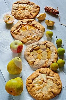 Various fruits tarts with fresh apples, plums and pears on gray concrete background. Vegetarian healthy galette - autumn dessert