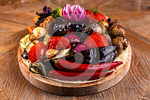 Various grilled vegetables on a round wooden Board. Tomatoes, zucchini, onions, eggplant, mushrooms, paprika