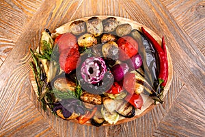 Various grilled vegetables on a round wooden Board. Tomatoes, zucchini, onions, eggplant, mushrooms, paprika