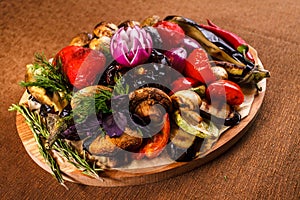 Various grilled vegetables on a round wooden Board. Tomatoes, zucchini, onions, eggplant, mushrooms, paprika