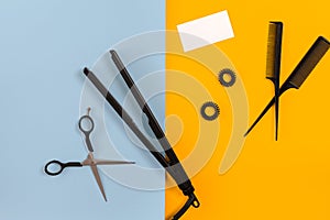 Various hair styling devices on the color blue, yellow paper background, top view