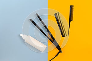 Various hair styling devices on the color blue, yellow paper background, top view photo