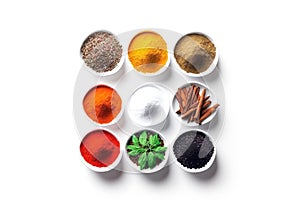 various herbs and spices in bowls on white surface with copy space