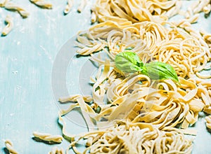 Various homemade fresh Italian pasta with flour and basil leaves