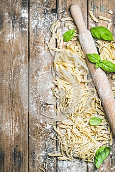 Various homemade fresh uncooked Italian pasta with flour, basil