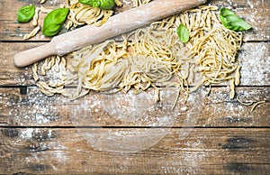 Various homemade fresh uncooked Italian pasta on wooden background