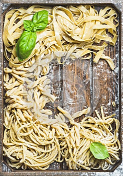 Various homemade uncooked Italian pasta in wooden tray
