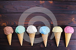 Various ice cream cones on wooden table, flat lay